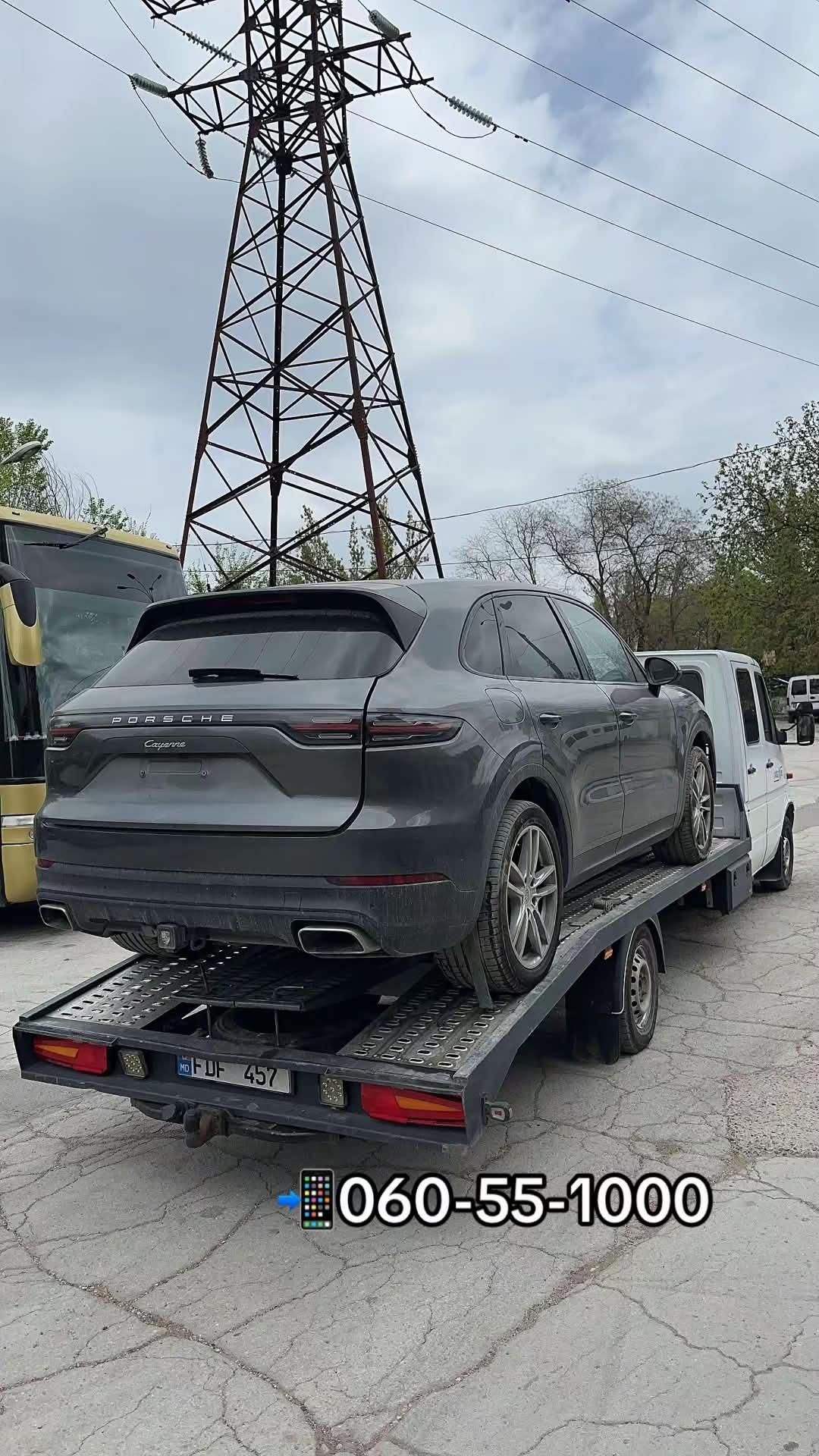 Evacuator auto transportând un Porsche Cayenne pe platformă